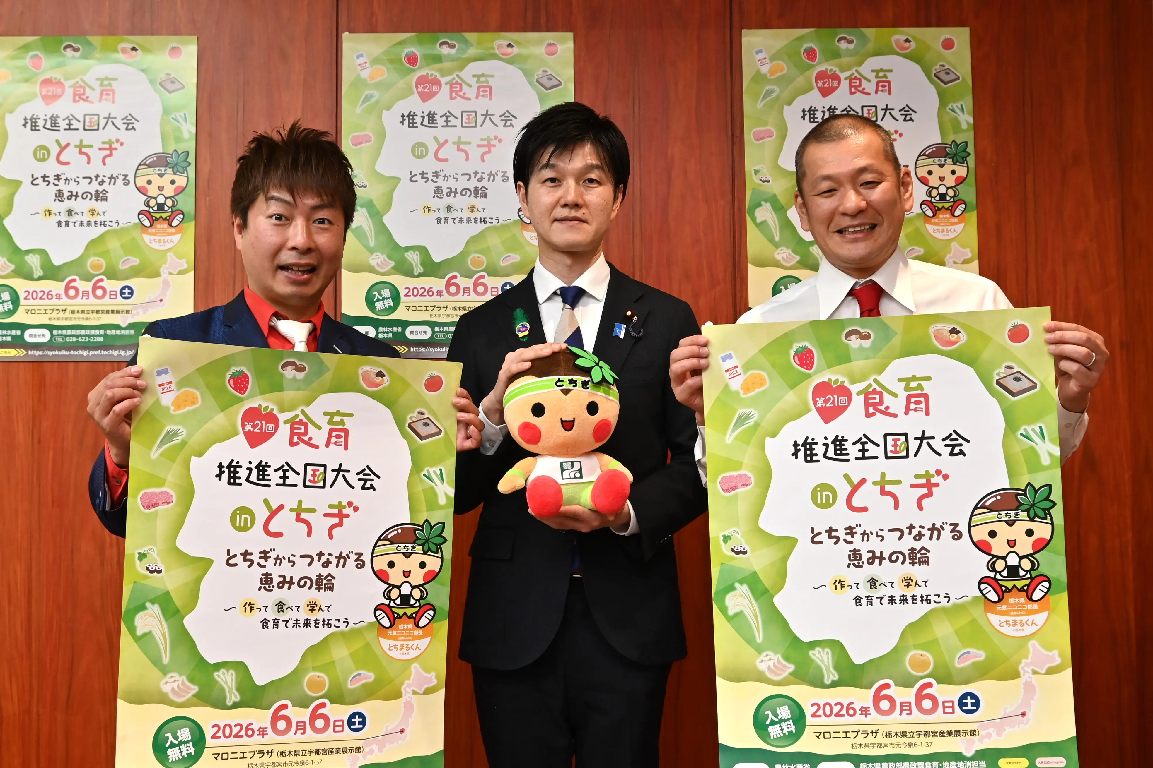 「第21回食育推進全国大会 in とちぎ」のポスターを手に鈴木農水大臣（中央）と記念撮影するU字工事