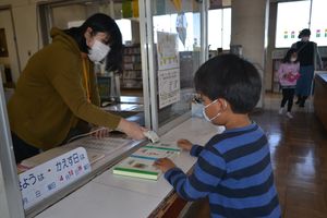 開放された学校図書室で本を借りる児童