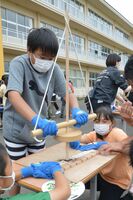 まいぎり式の火起こしに挑戦する児童たち
