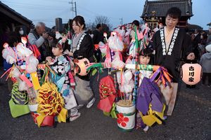 晴れ着姿で花桶をかついで練り歩く女児たち＝25日午後５時、小山市寒川